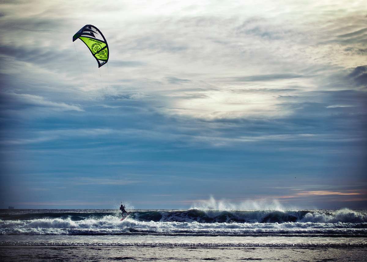 sea person riding surfboard kite
