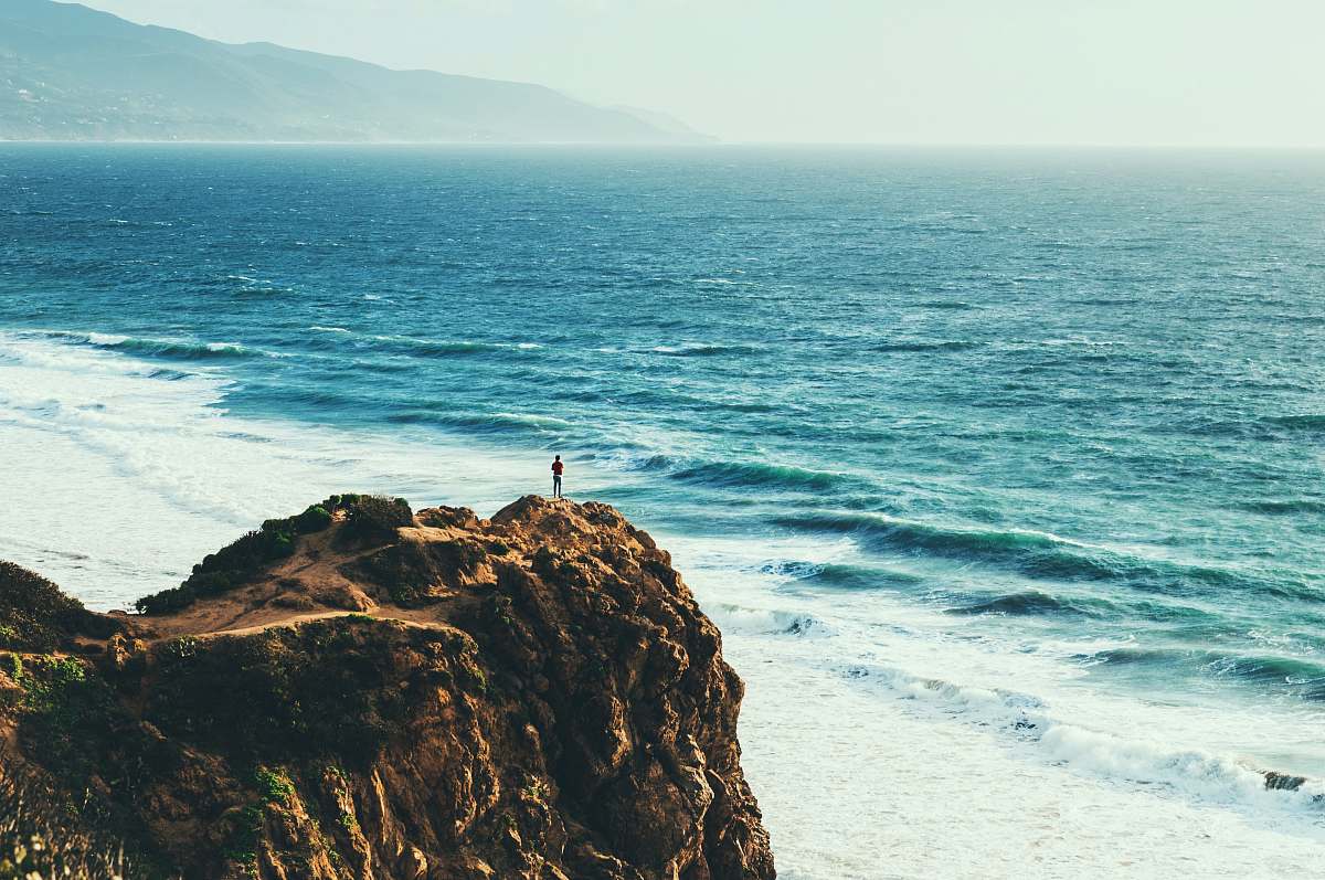 cliff person standing near body of water coast