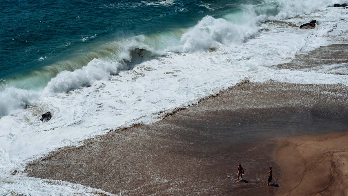water two person on seashore facing ocean waves sea