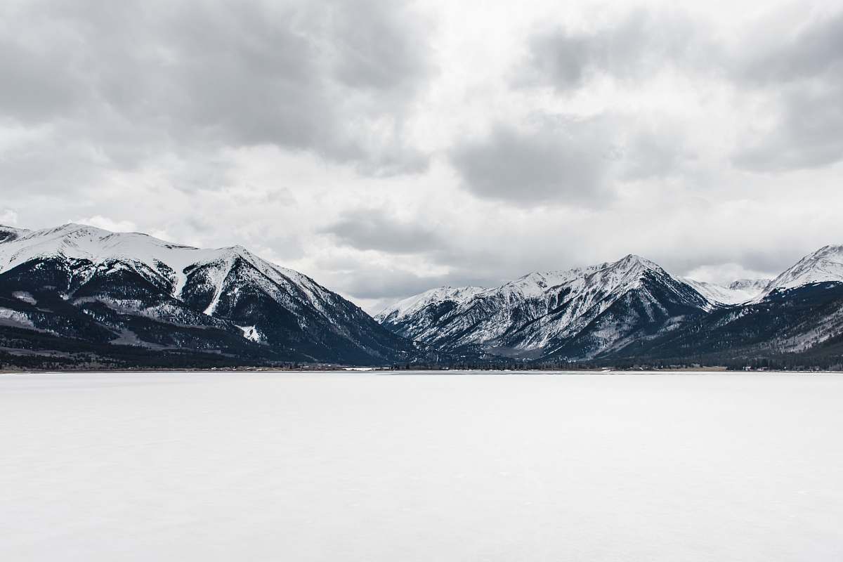 mountain body of water near mountain peak during daytime snow