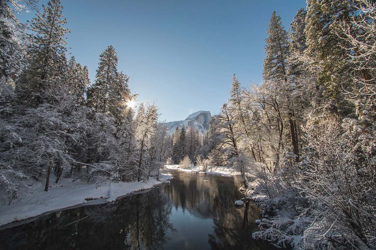 snow lake in middle of forest with pine trees yosemite valley