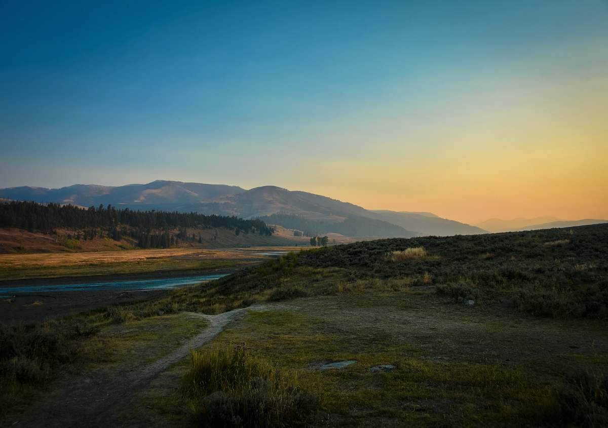 field landscape photography of river and mountain grassland