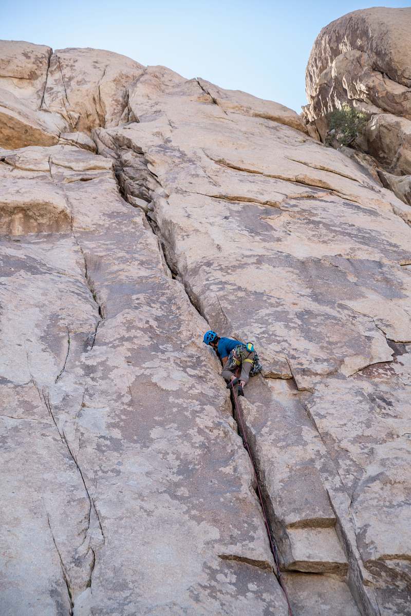climbing person in blue shirt climbing on brown mountain adventure