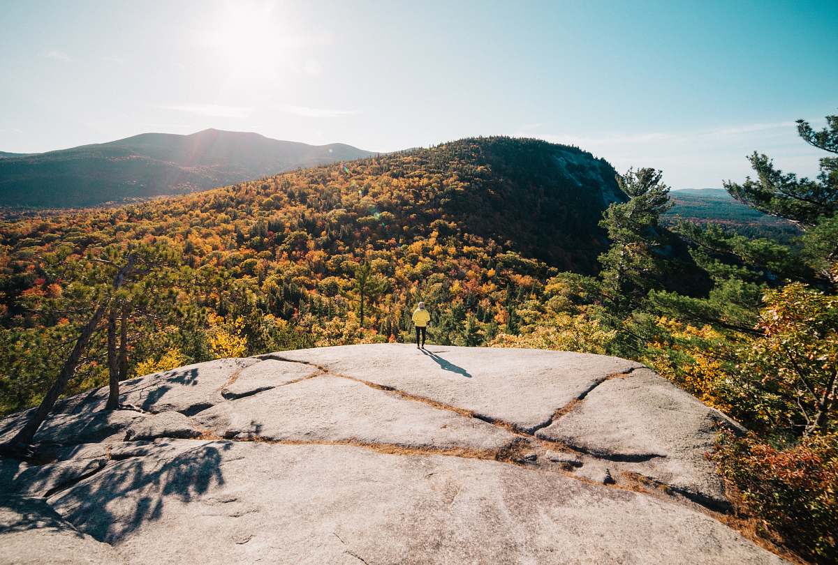 mountain person standing on rock cliff under clear blue skies at daytime cathedral ledge road