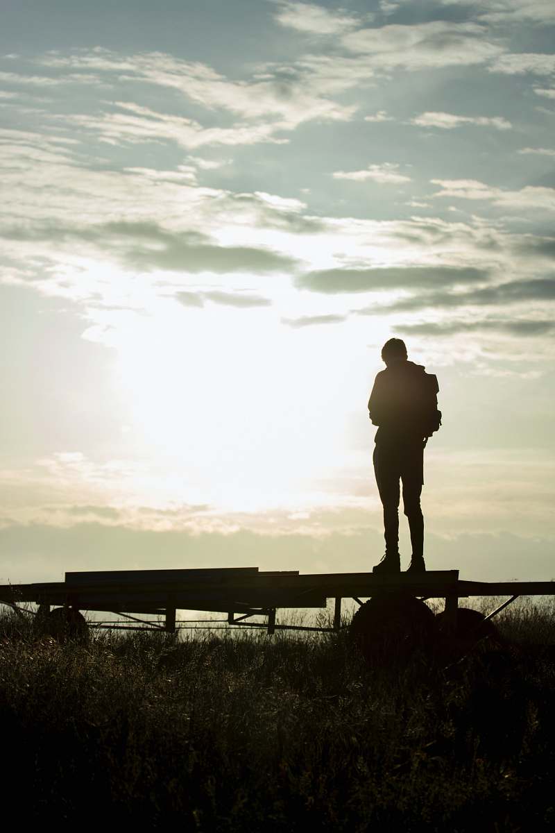 human silhouette of man standing on wooden fence during sunset person