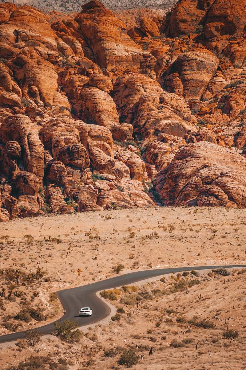 nature white vehicle travelling on curve road surrounded with brown mountains at daytime mountain