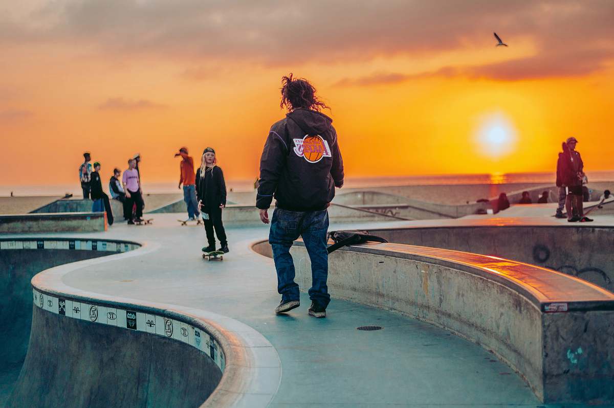 apparel man in black jacket standing on gray concrete floor during sunset clothing