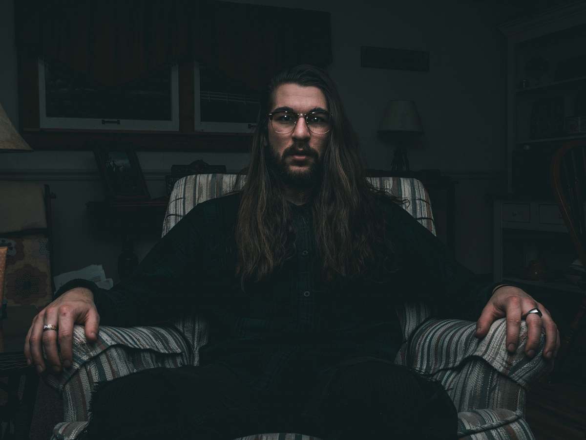 human man in black dress shirt sitting on sofa chair person