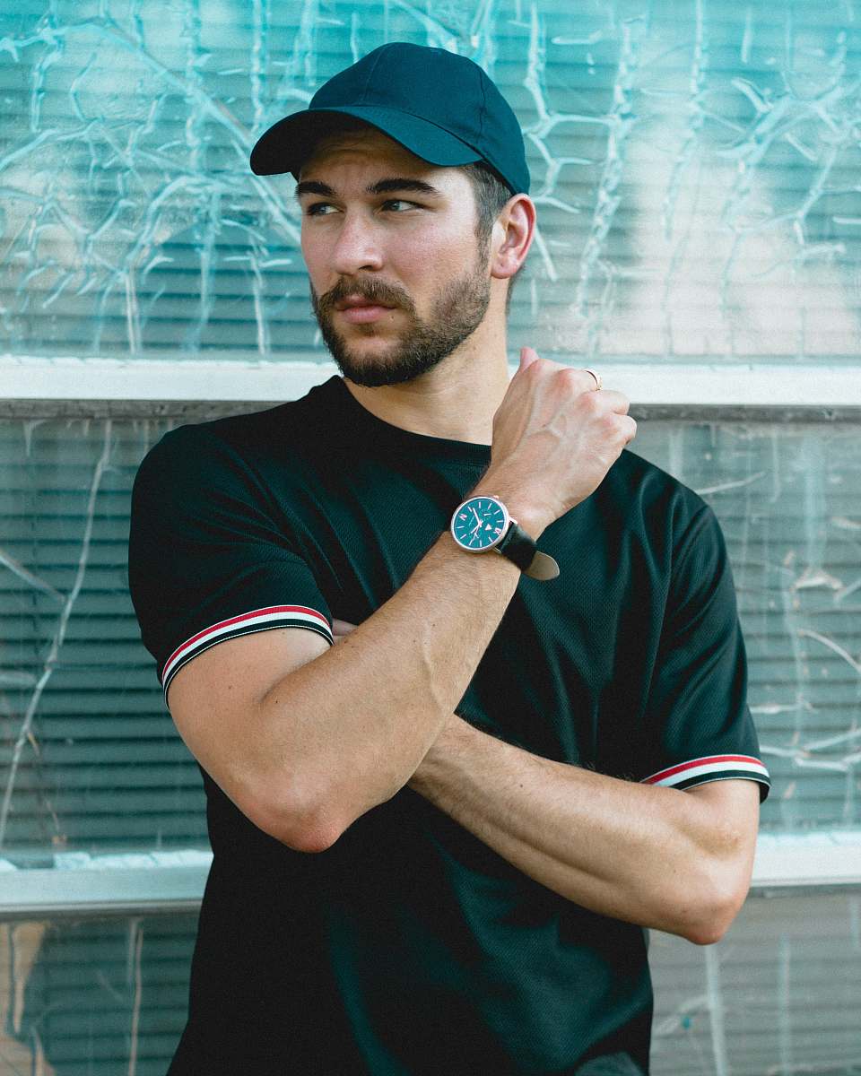 human man wearing black crew-neck shirt and black cap in front of glass wall person