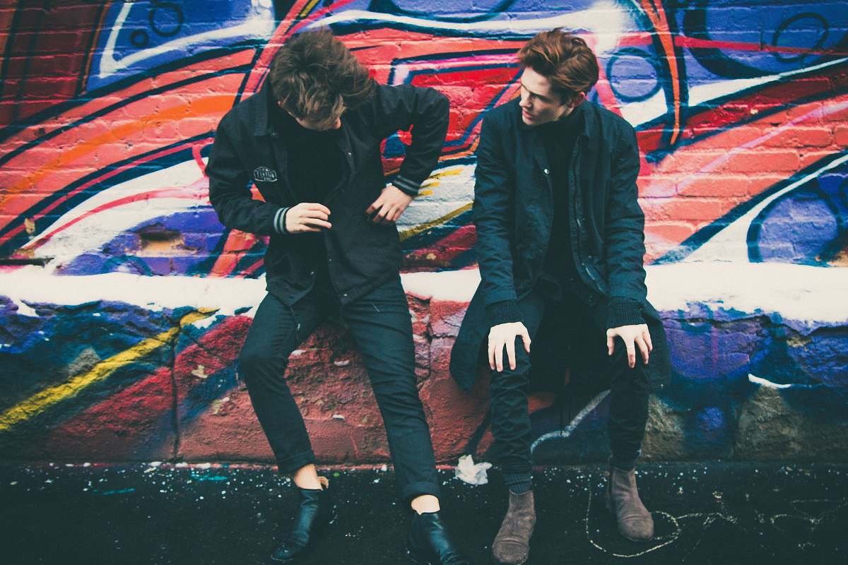 human two men leaning against graffiti wall art person