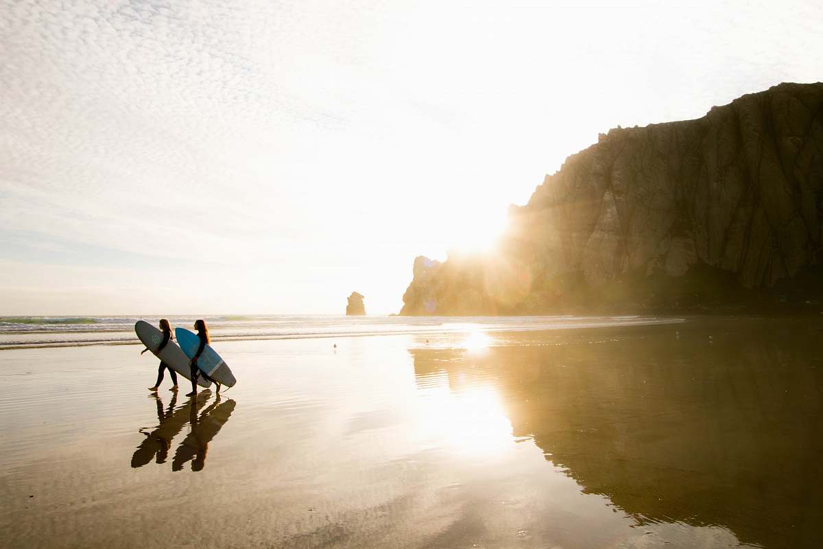 human two people carrying surfboards while walking on seashore person