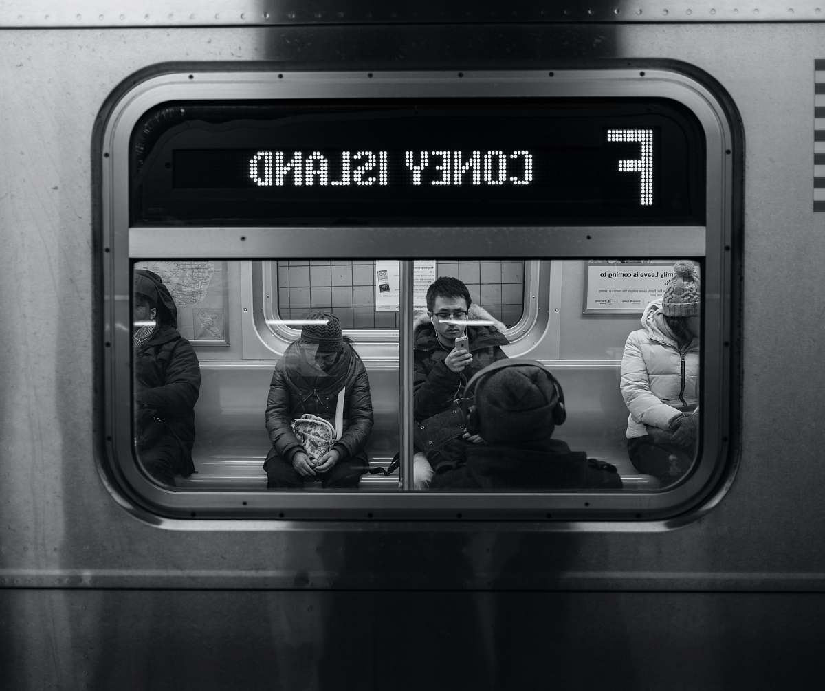 black-and-white grayscale photo of persons sitting on train subway