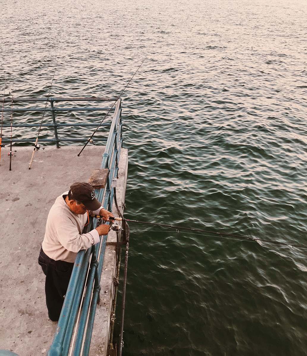 people man holding black fishing rod standing on boat deck at daytime fishing