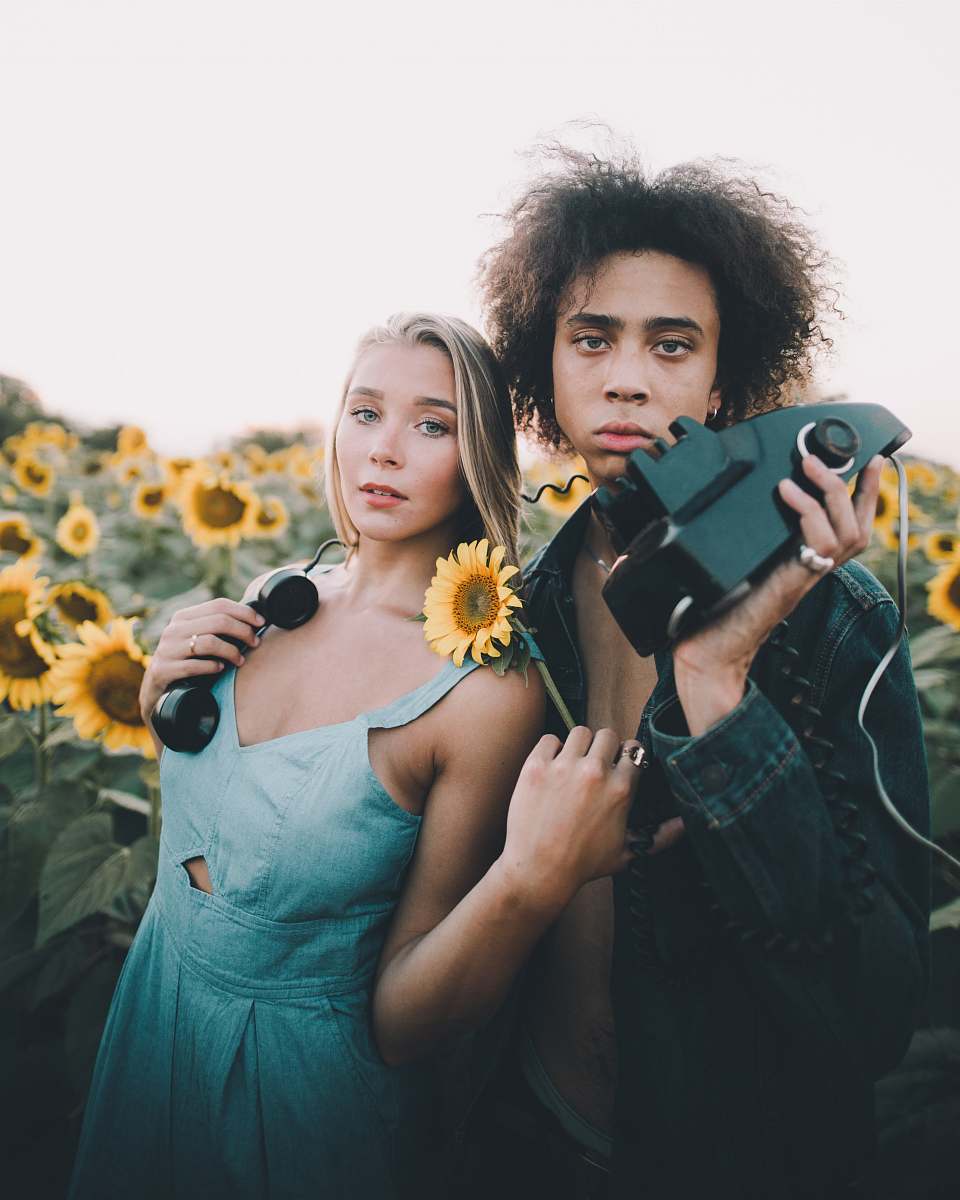 human man holding corded device standing beside woman wearing blue dress people