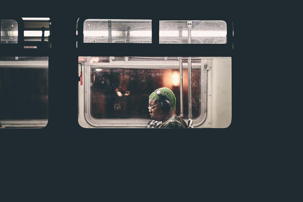 human man sitting inside train wearing black headphones people