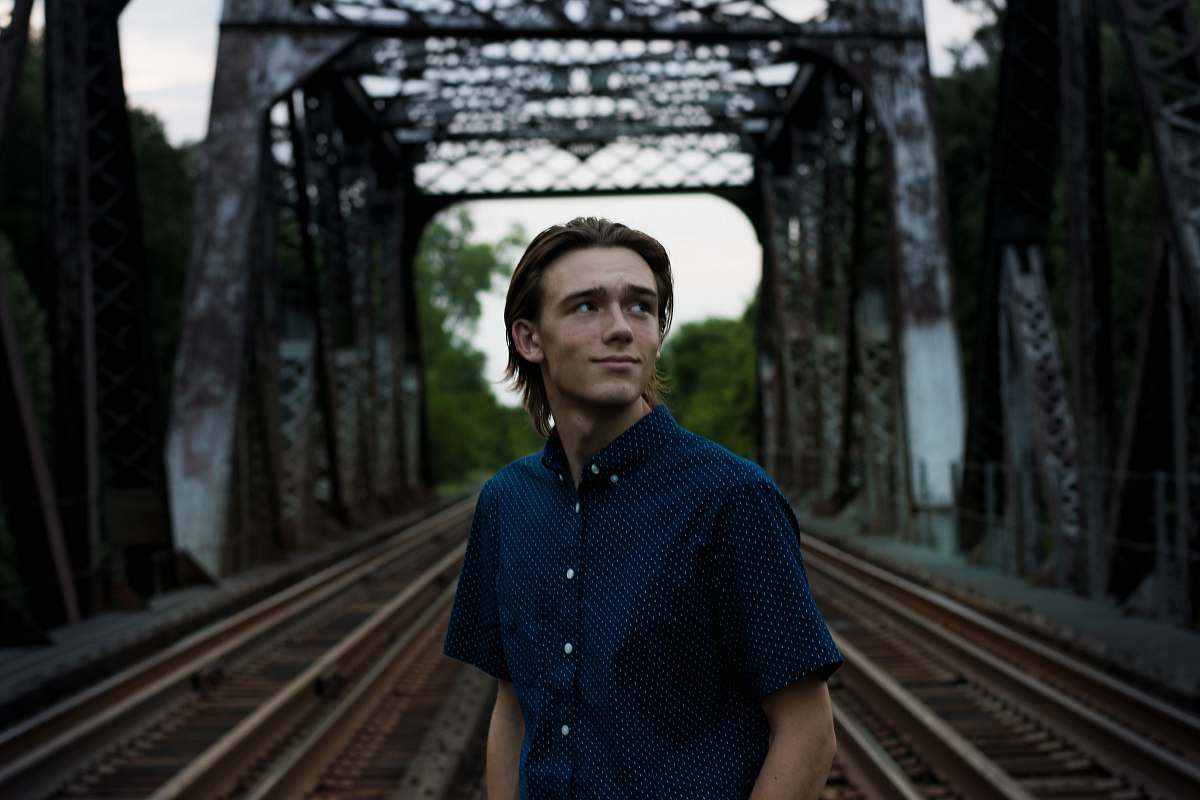 human man staining in the middle of a bridge rail people
