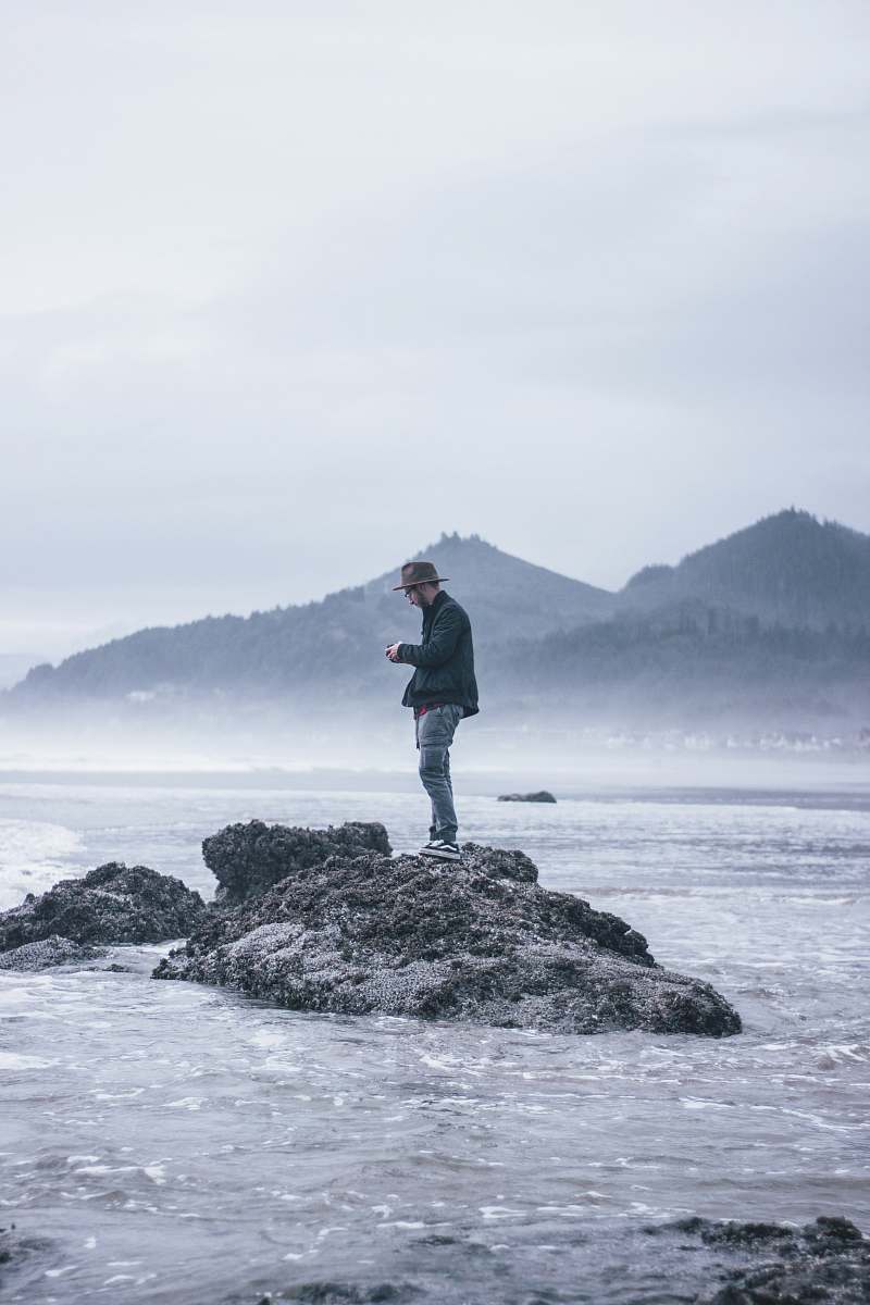 human man standing beside body of water during daytime standing