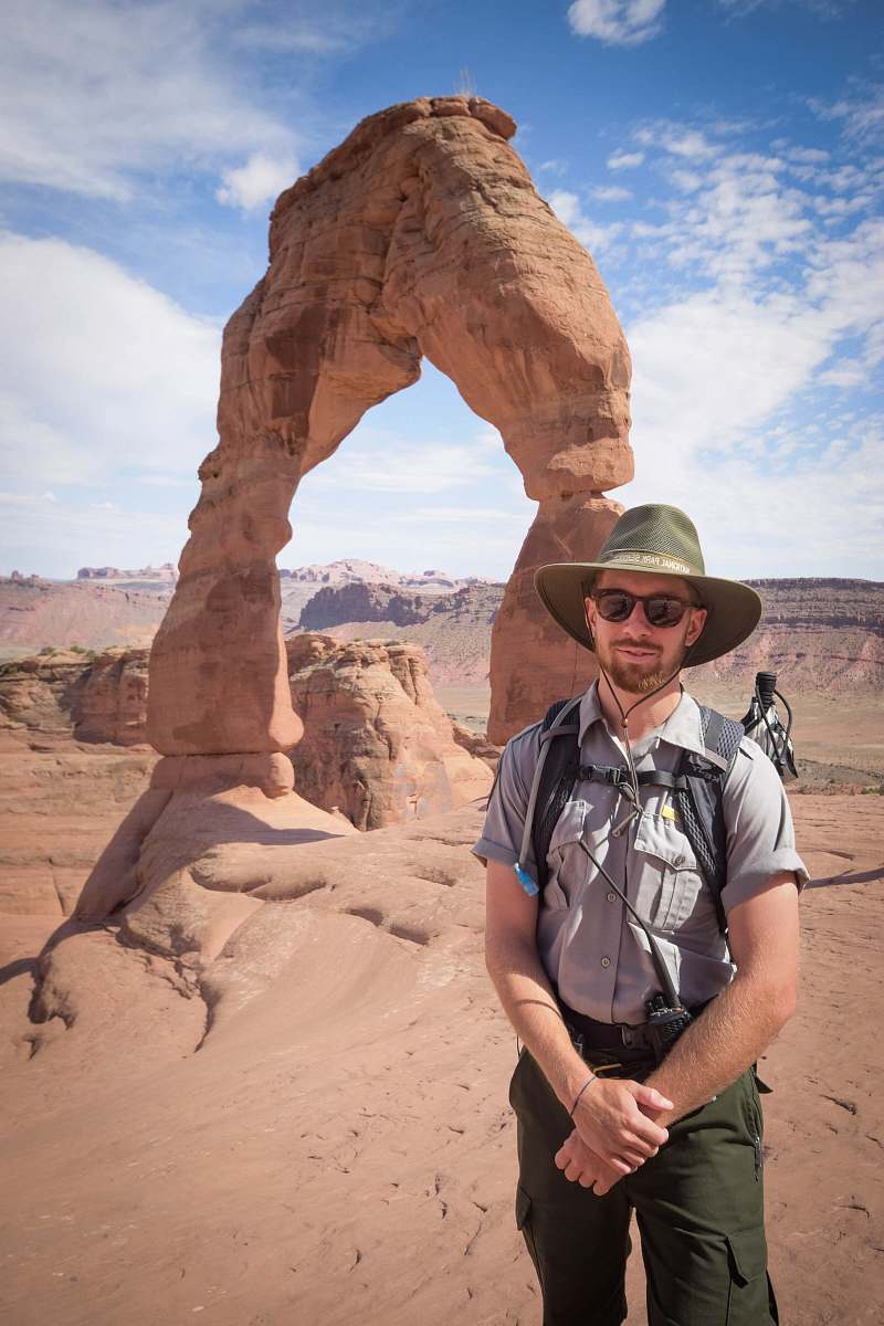human man standing near Delicate Arch people