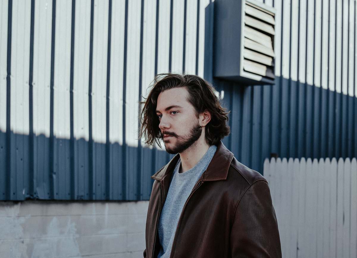 human man wearing brown leather jacket standing against grey background people