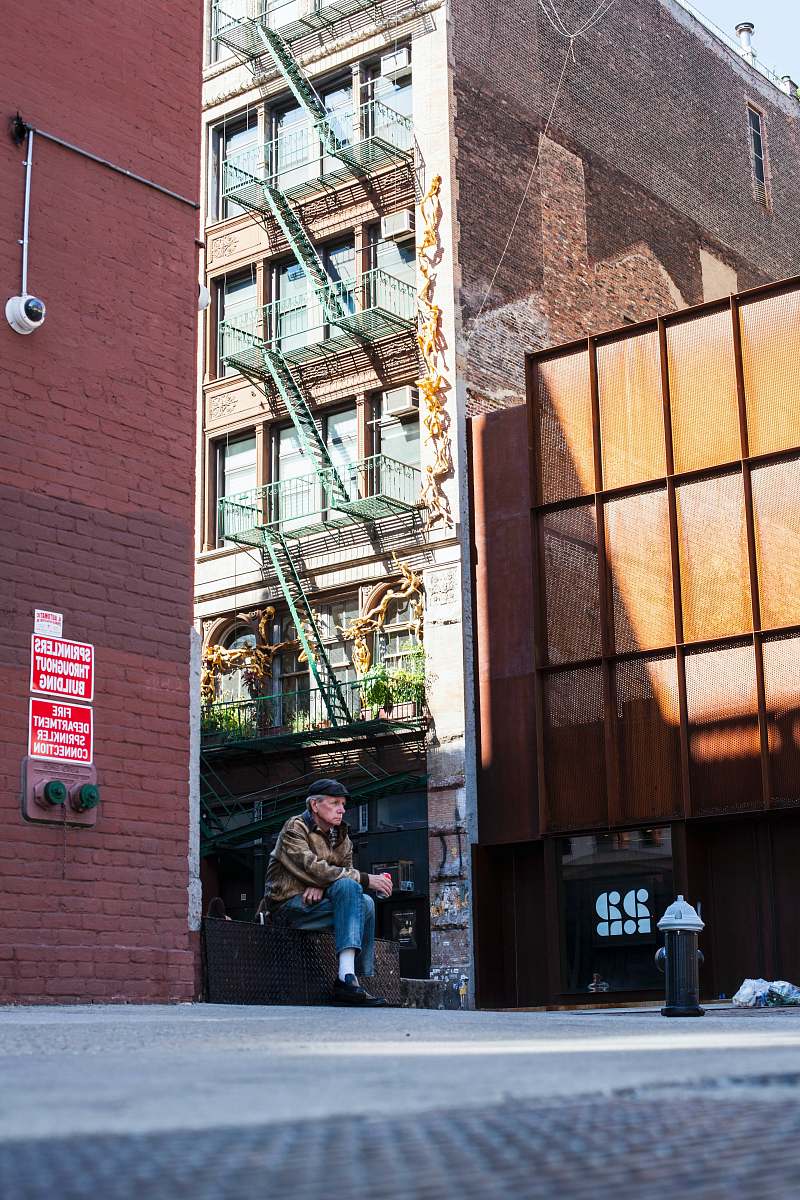 human person sitting on bench beside building people