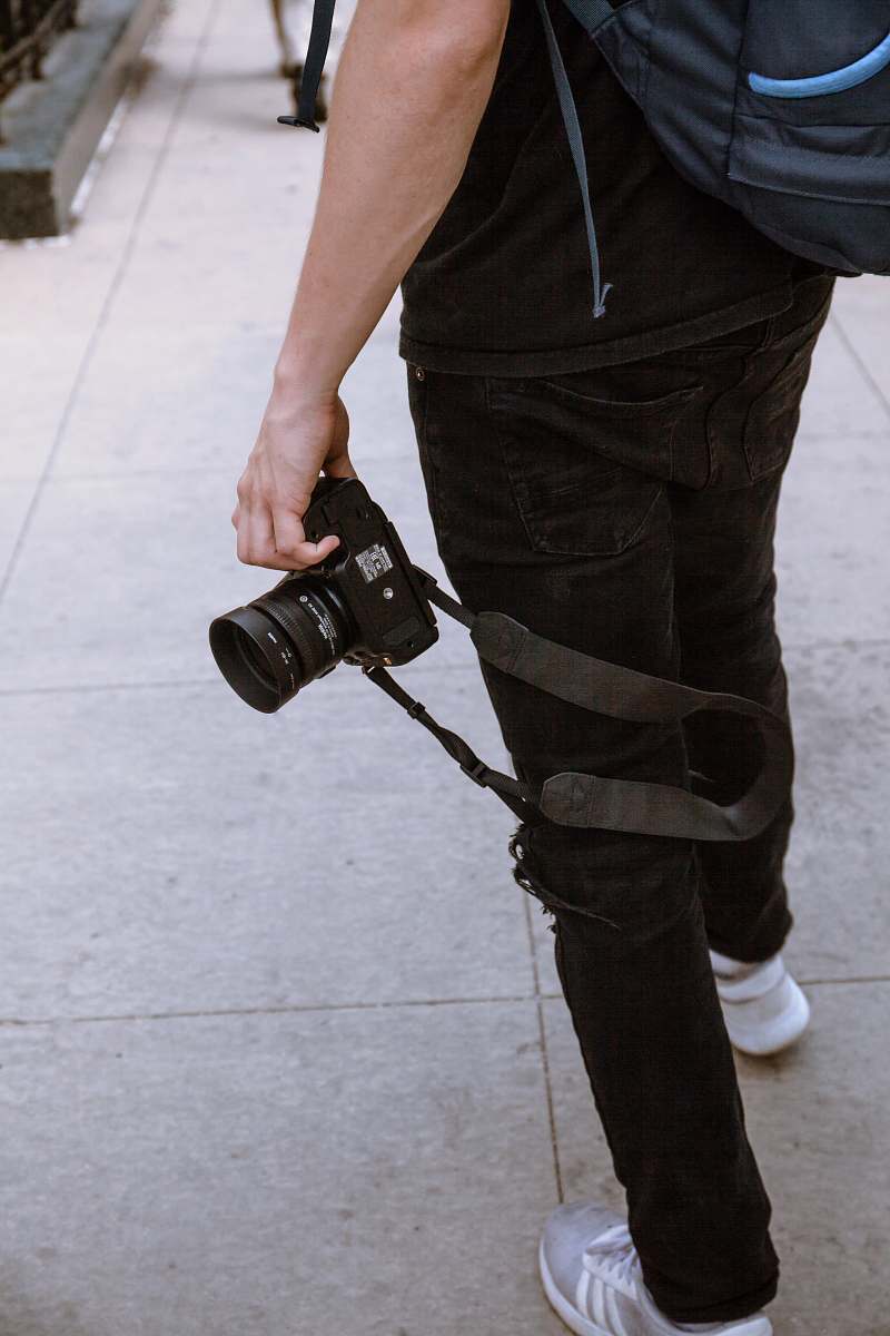 people person wearing black jeans holding black DSLR camera human