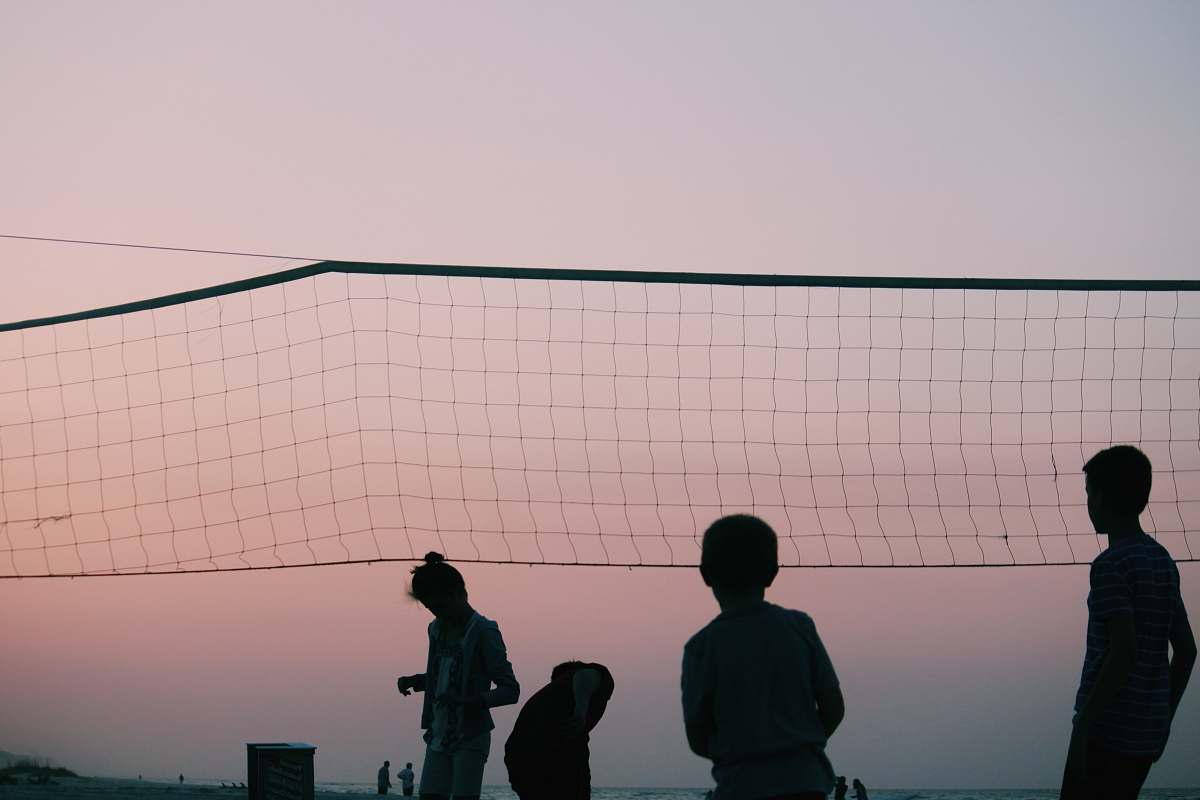 human silhouette of four people playing volleyball during nighttime people