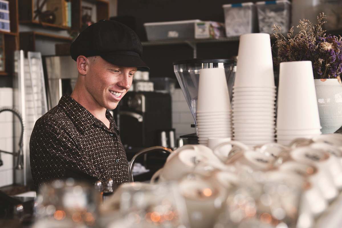 human smiling man beside cups people