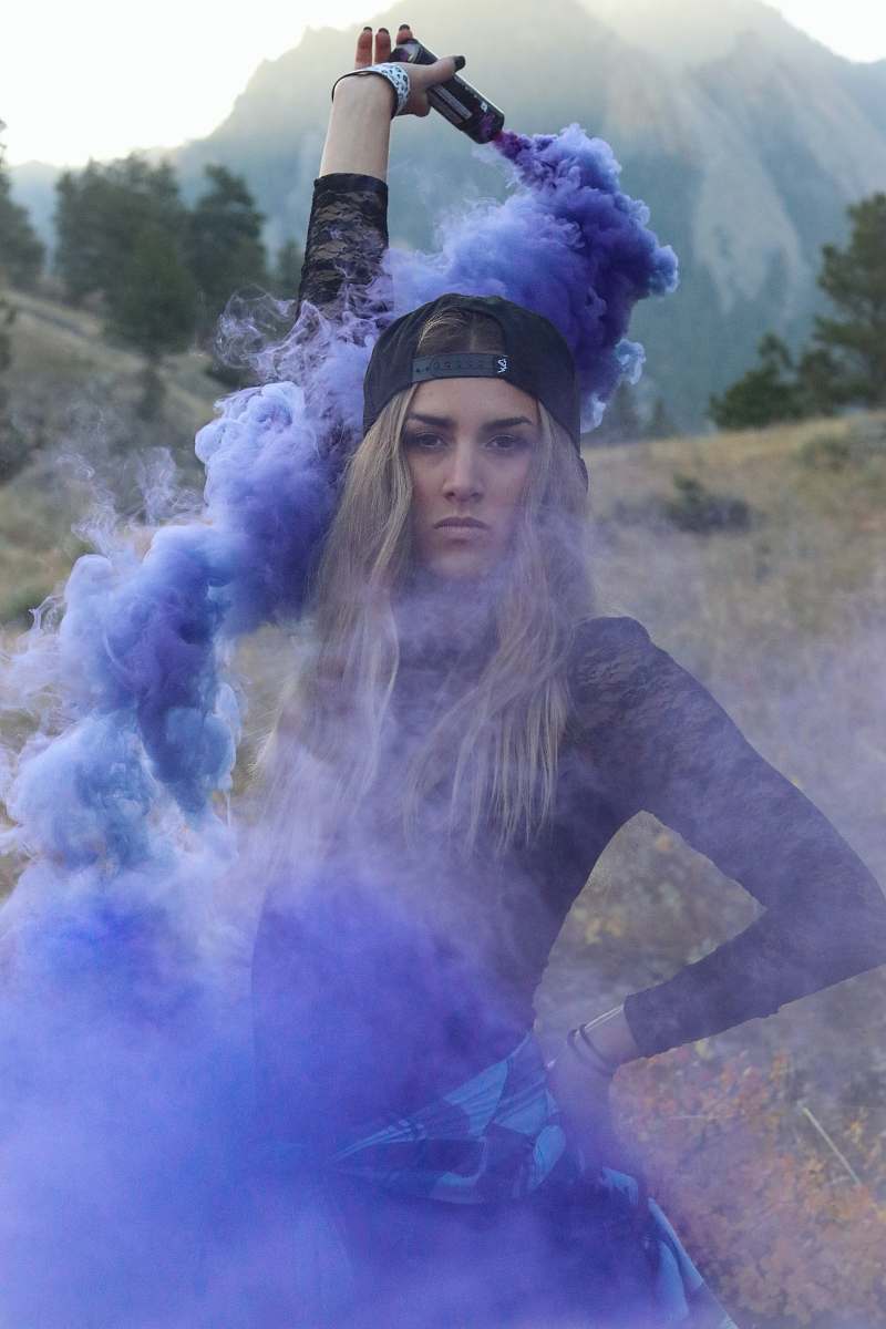 human woman raising purple smoke bomb during daytime people