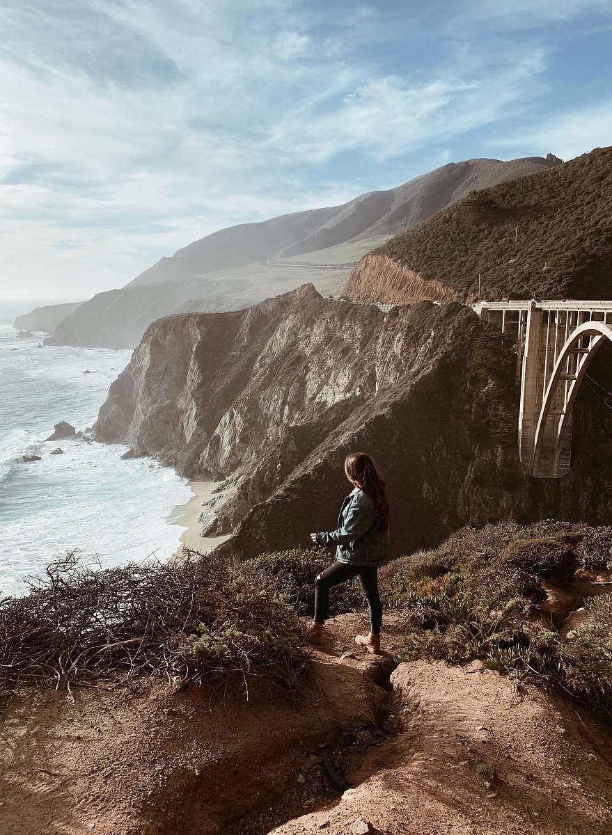 human woman standing on top of mountain looking at sea promontory