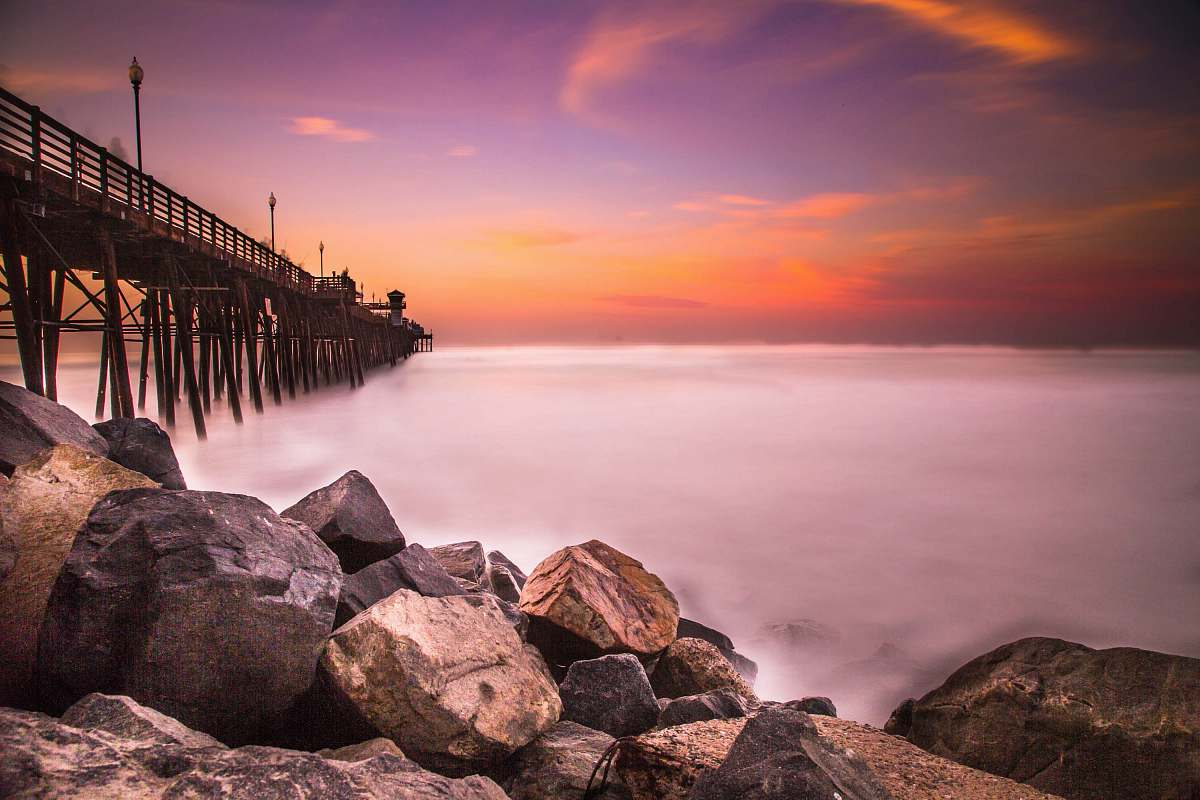 ocean low-angle photography of rocks near bridge coast