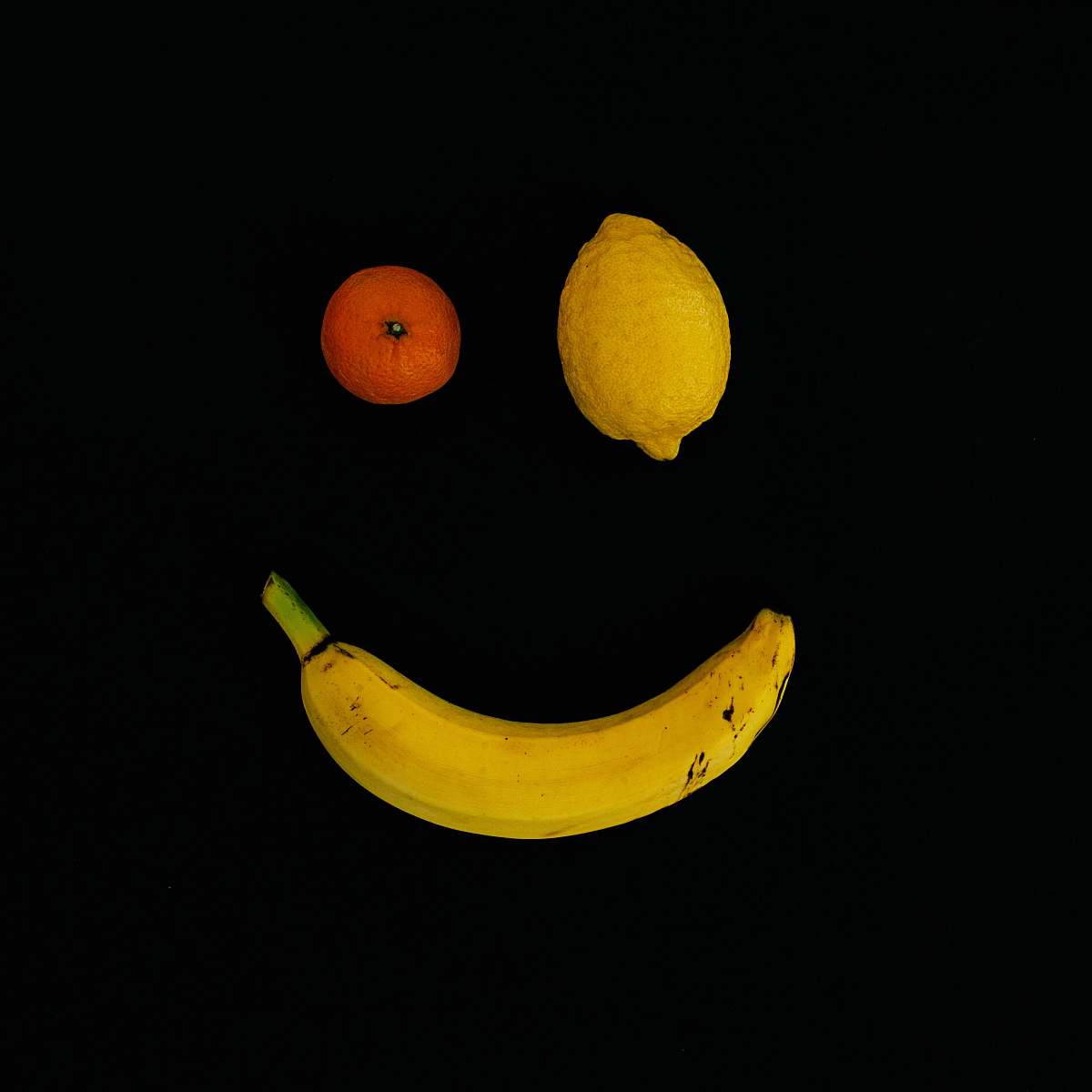 food yellow lime, orange fruit, and yellow banana with smile formation fruit