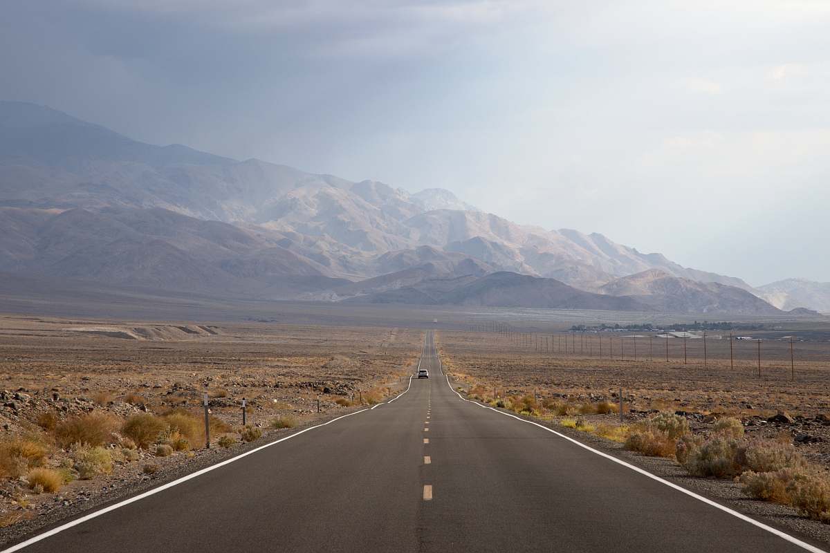 freeway asphalt road going to mountain between grass field death valley national park