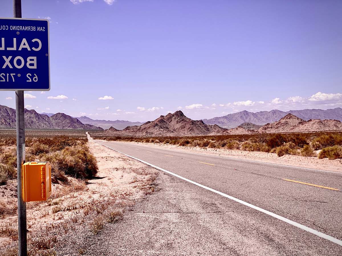 freeway gray concrete road near brown mountain under blue sky during daytime highway
