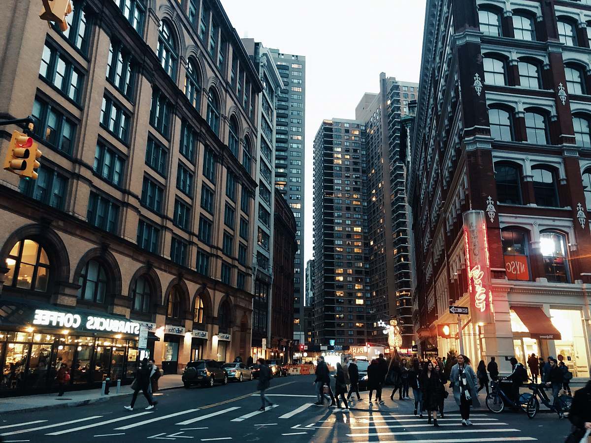 urban people walking near street surrounded by buildings during daytime city
