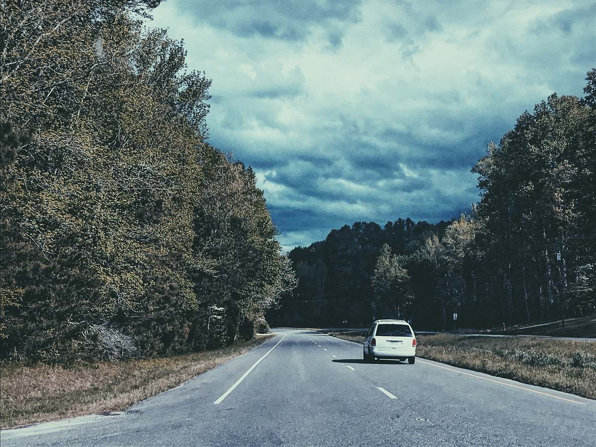 asphalt white vehicle on road near trees during daytime tarmac