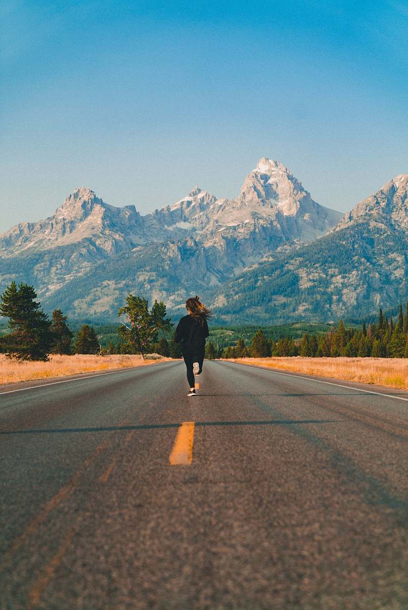 asphalt woman walking on road during daytime tarmac
