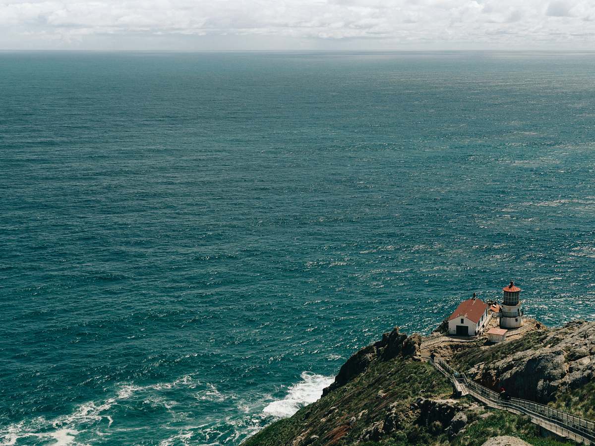lighthouse house on hill in front body of water coast
