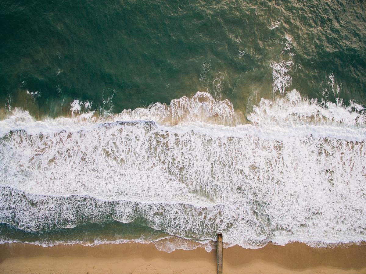 water top view photography of brown beach sand with teal ocean water during daytime ocean