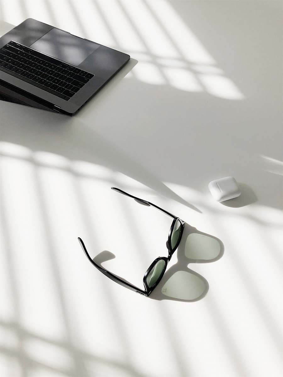 sunglass flat-lay photography of wayfarer-style sunglasses and MacBook Pro glasses
