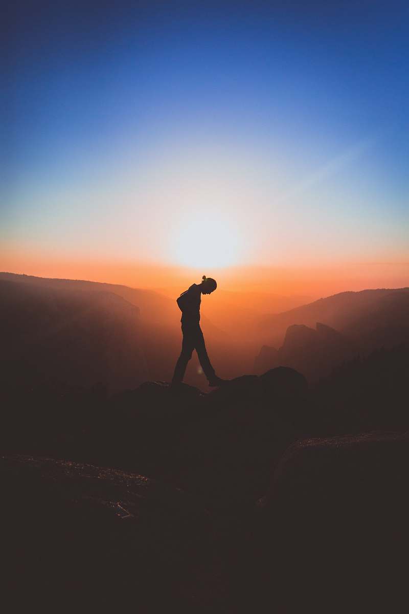 sunset silhouette of man standing on mountain peak silhouette