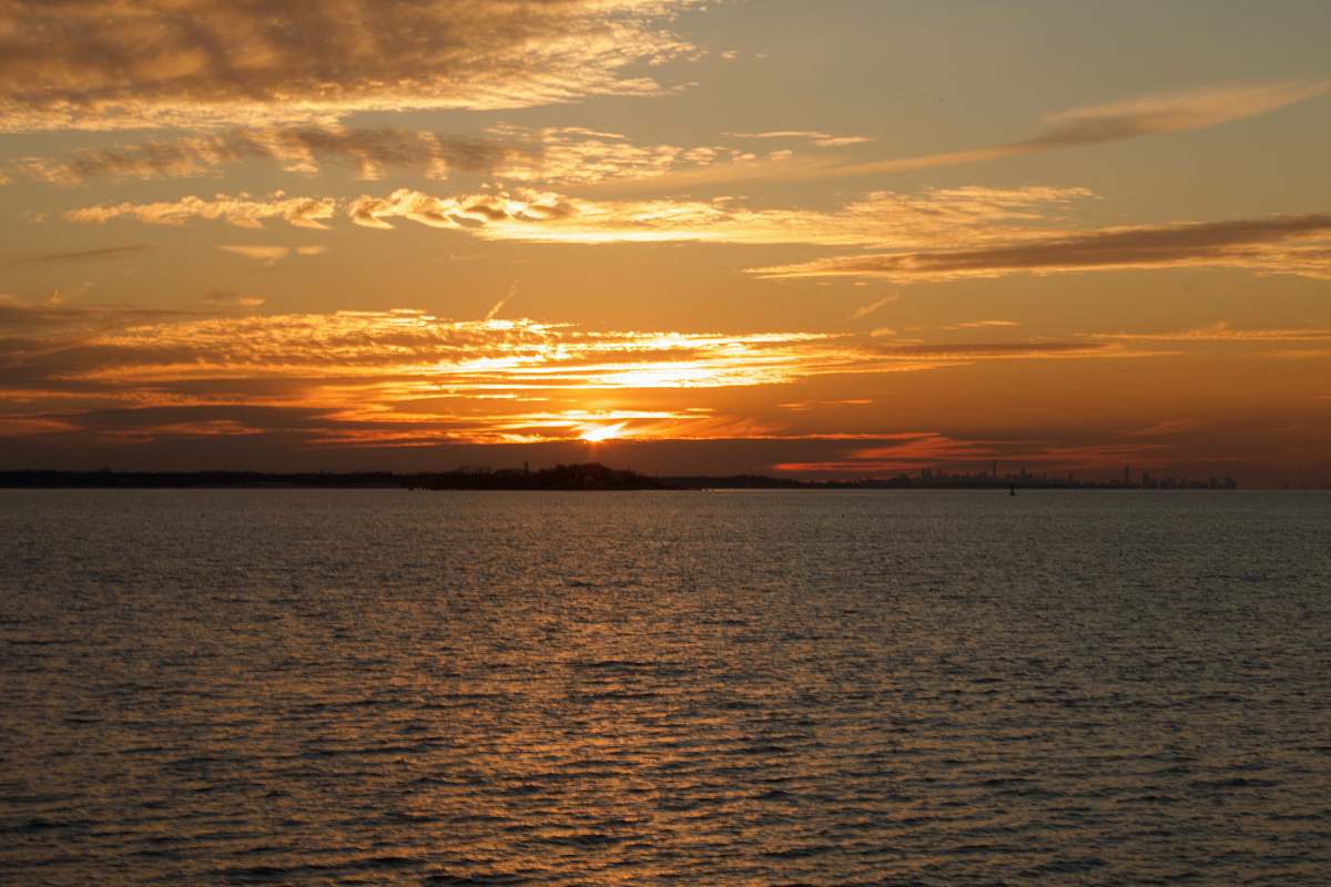 sunset silhouette of mountain in front of body of water ocean
