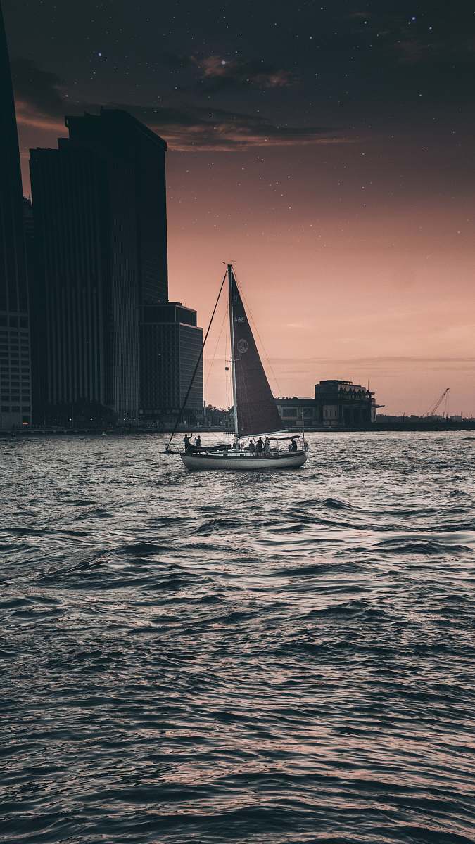 Capture the essence of urban serenity with this striking black and gray sailboat gliding gracefully across the tranquil waters. The city skyline serves as a breathtaking backdrop, creating a perfect contrast between the natural beauty of the watercraft and the architectural charm of the metropolis. Ideal for travel blogs, advertisements, and lifestyle magazines, this image embodies adventure, relaxation, and the allure of sailing.
