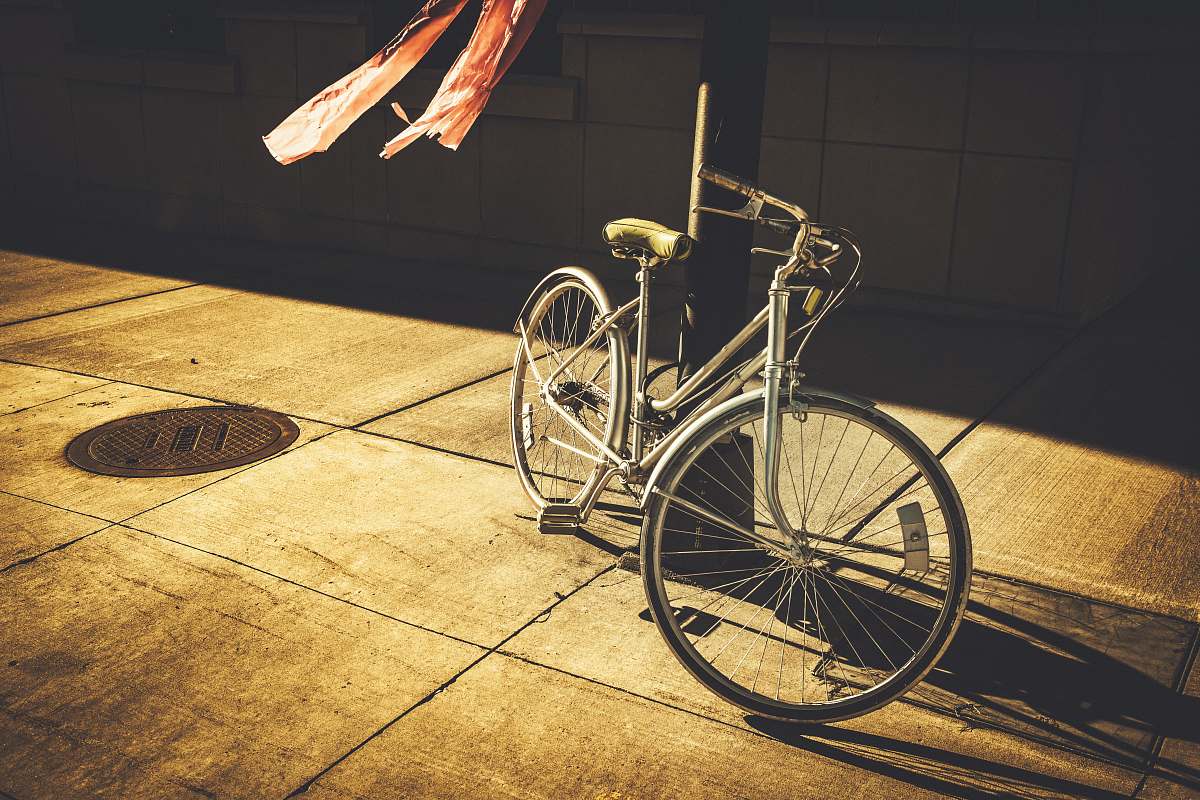 bicycle gray step-through bike leaning on black post bike