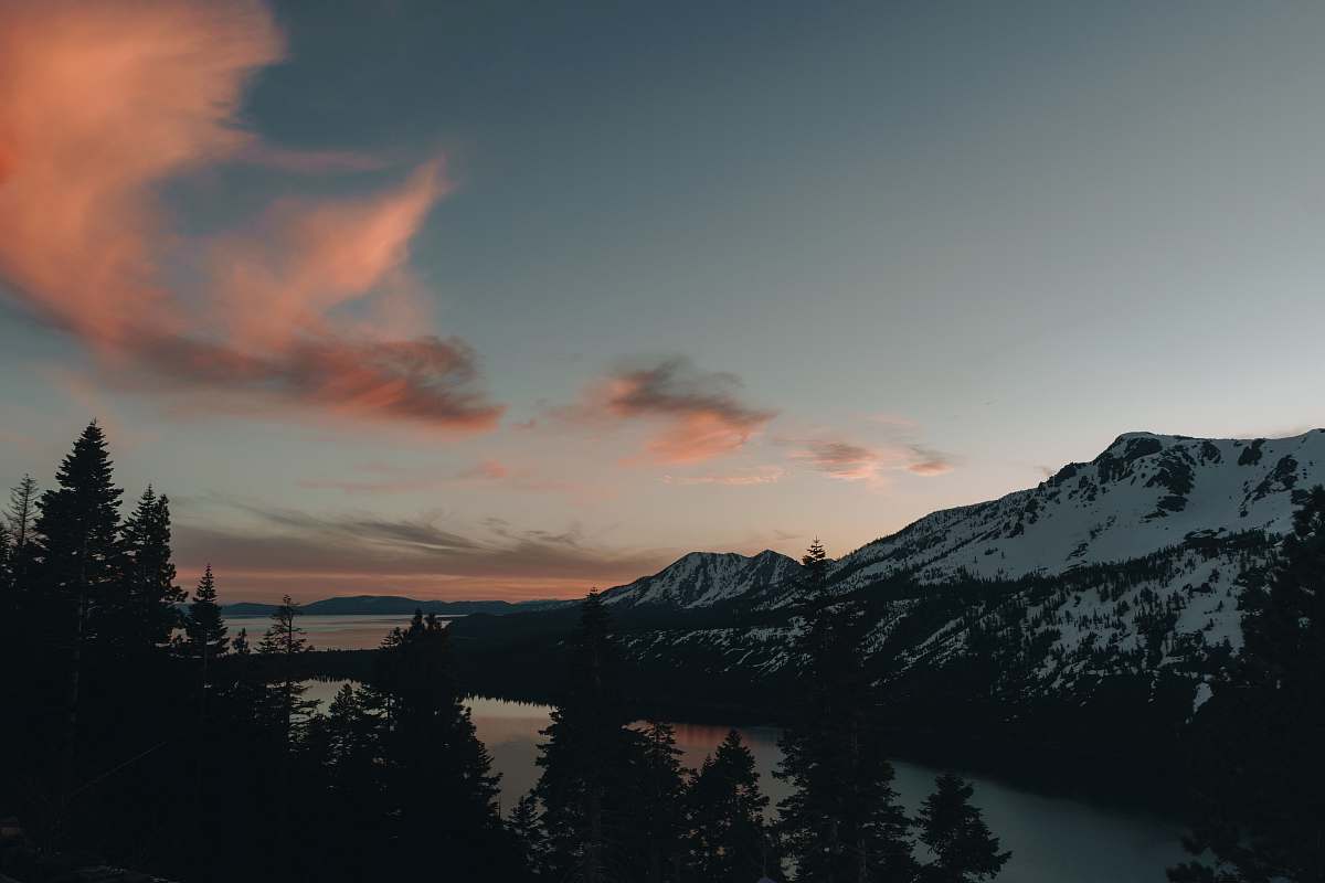 abies body of water within snow-covered mountain range during daytime conifer