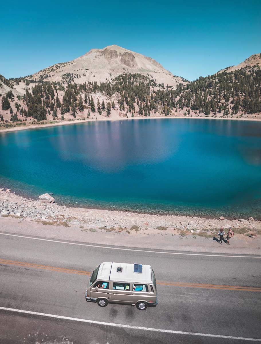 transportation vehicle travelling on road near lake and mountain vehicle