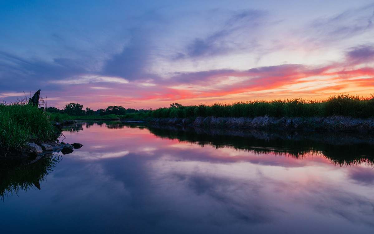dusk photo of body of water surrounded with grass field nature