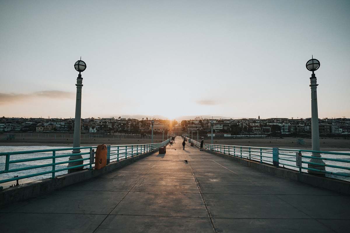 path photography of person walking on bridge during daytime pier