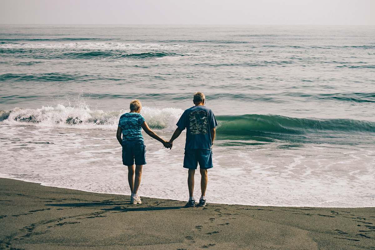 clothing man and woman holding hands together while standing on seashore shorts