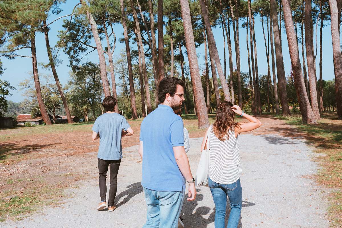 Capture the essence of adventure and style with this vibrant image of two men and a woman strolling along a picturesque path flanked by lush trees. Dressed in trendy denim, this fashionable trio embodies a perfect blend of urban chic and natural beauty, making it an ideal choice for bloggers, lifestyle magazines, and outdoor brands seeking to evoke themes of connection, exploration, and modern fashion.