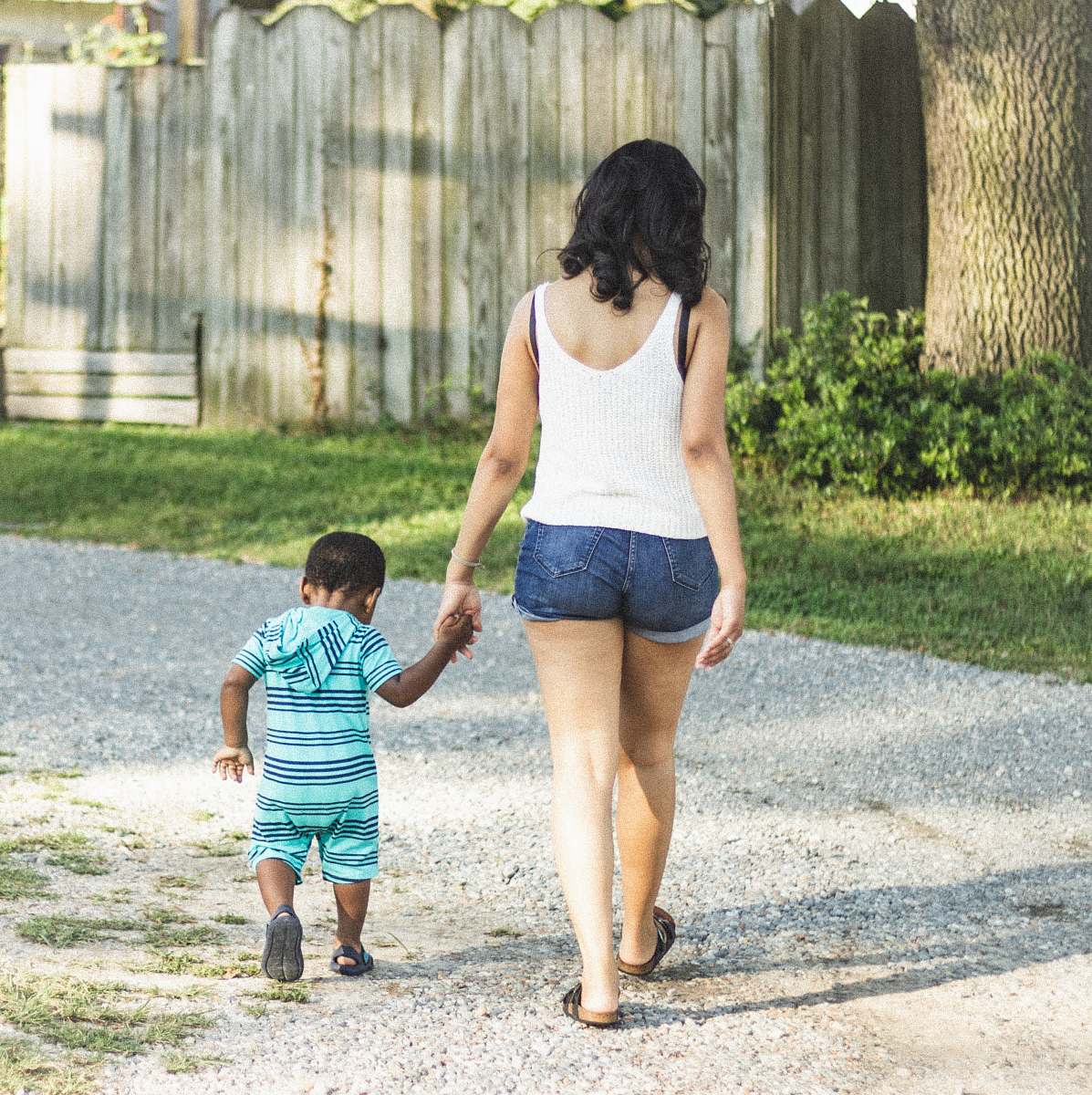 shorts woman and boy holding hands walking near green grass at daytime clothing